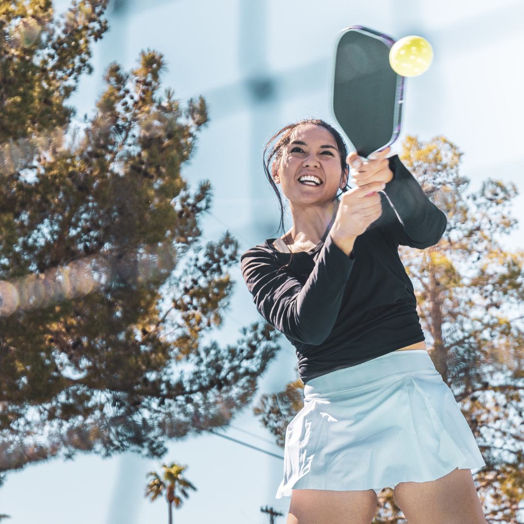 Female athlete playing pickleball outdoors, emphasizing hydration and performance