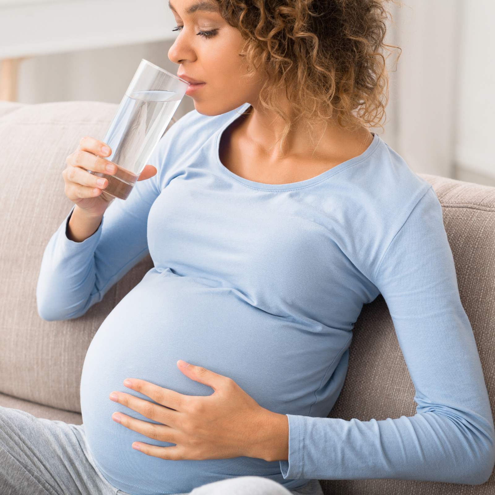 Pregnant woman drinking water to maintain hydration and electrolyte balance