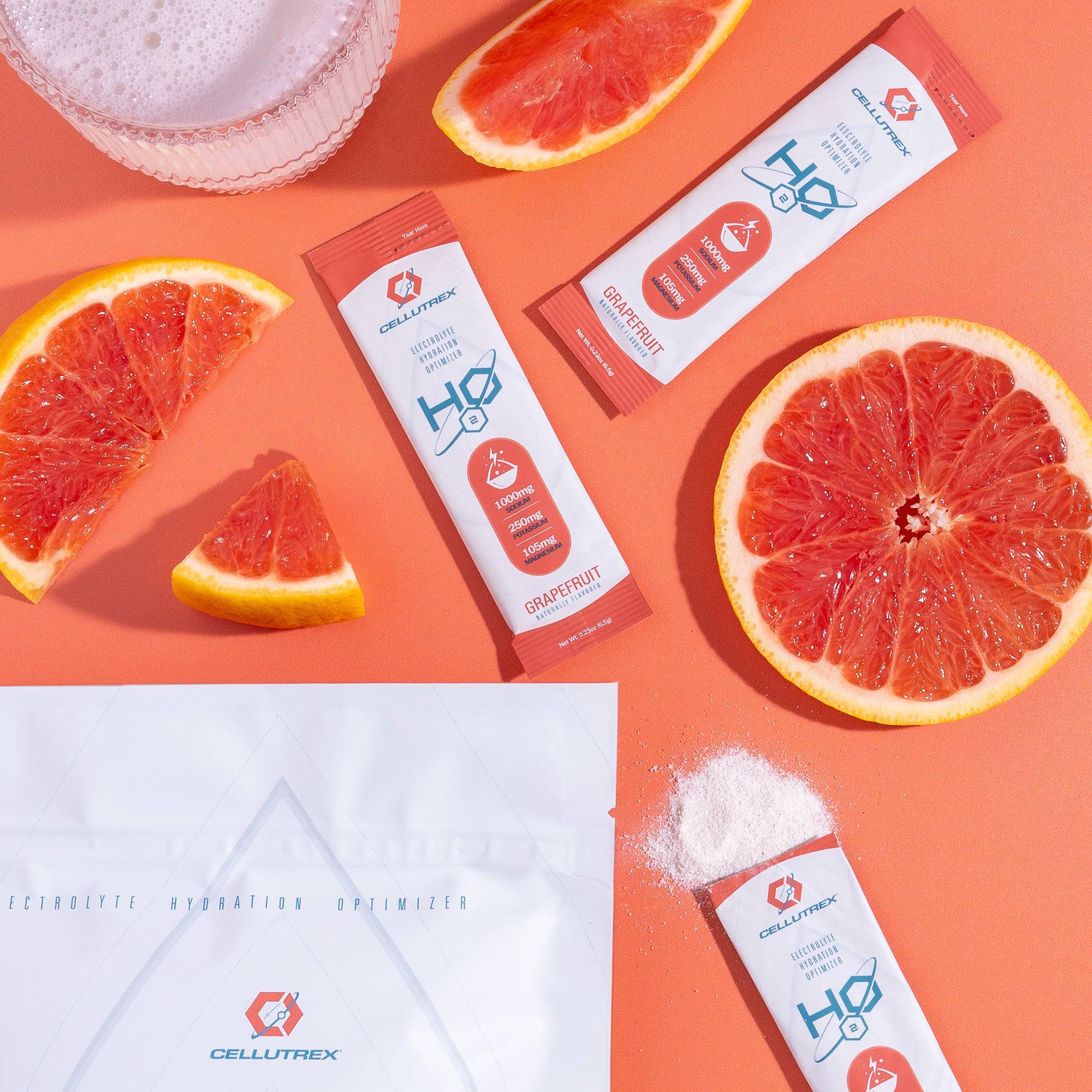 H2O Electrolytes™ Grapefruit zero sugar electrolyte powder with sliced grapefruit, hydration powder, and a bubbly mixed drink on a bold orange background. Fast-absorbing electrolyte packets for hydration and energy.